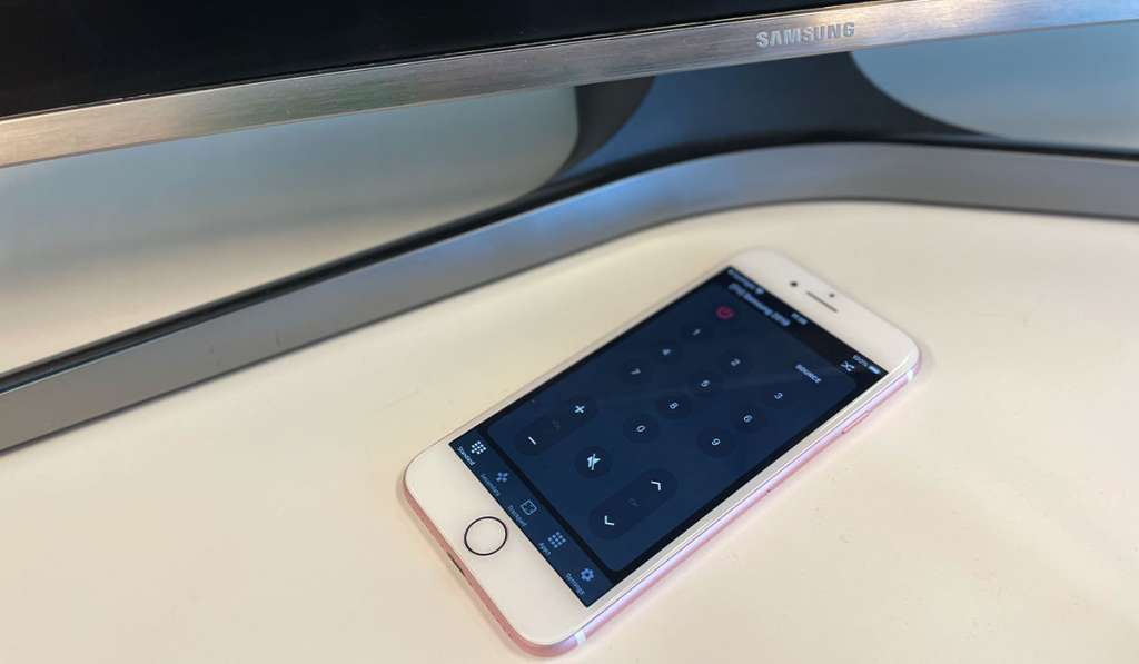 A white iPhone with ControlMeister in the screen. A stand for a Samsung TV